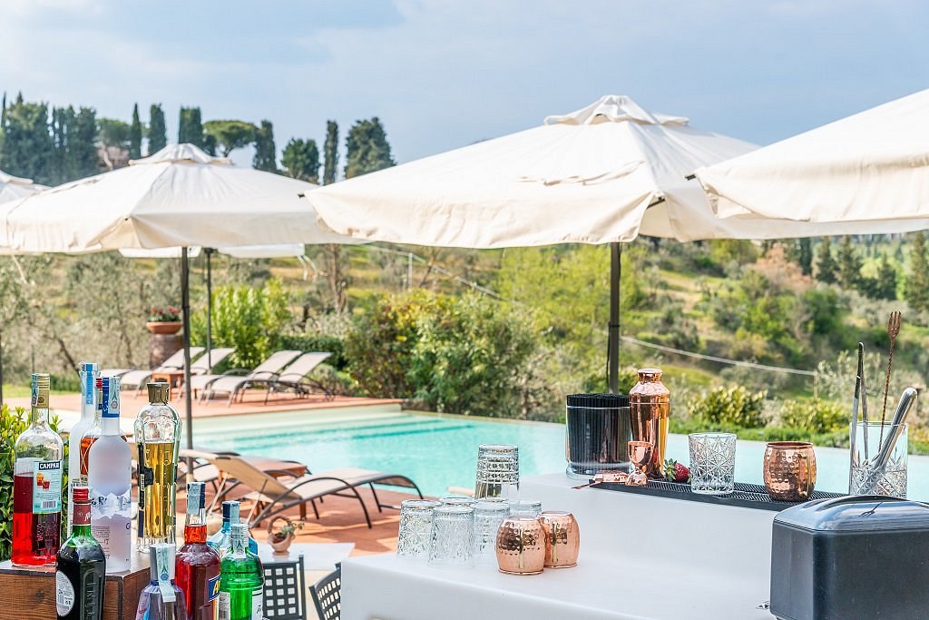 The cocktail bar by the pool with spirits, copper shakers and the Tuscan countryside beyond